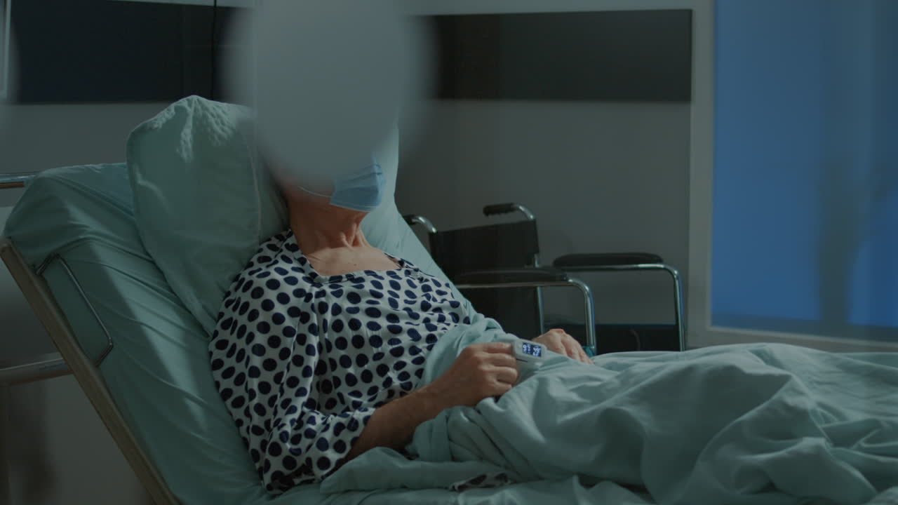 Sick patient sitting in hospital ward bed with face mask
