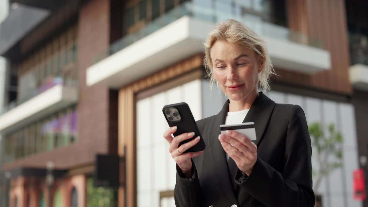 Businesswoman making online payment with credit card and mobile phone outdoors