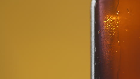 close up of condensation droplets running down side of revolving bottle of cold beer or soft drink with copy space