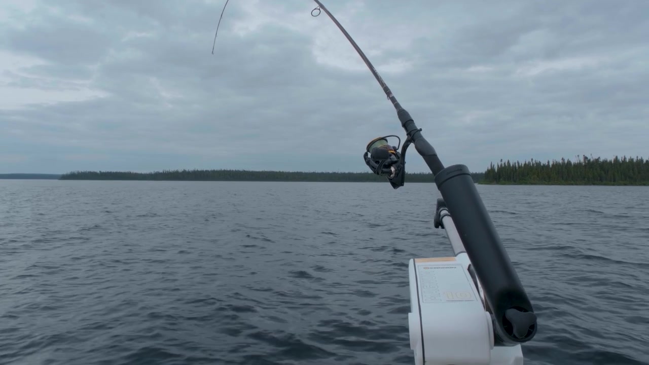 Naturskön vy från en fiskebåt med en fiskerulle och en vidsträckt nordlig sjö.