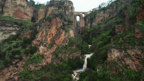 Flyover-aerial-4k-view-of-waterfall-and-Puente-Nuevo-bridge-in-Ronda,-Andalusia,-Spain