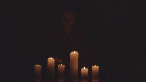 person lighting candles in dark room