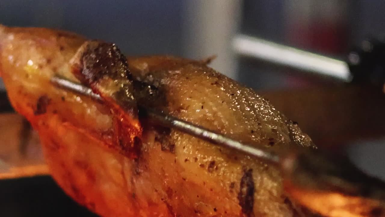 Detailed view of a duck roasting on a skewer, highlighting its crispy, golden skin and succulent texture.