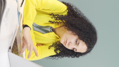 Vertical-video-of-Young-woman-looking-at-laptop-is-unmotivated-and-bored.