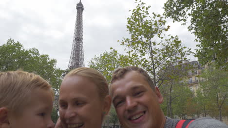 familia con un niño haciendo un video selfie contra la torre eiffel