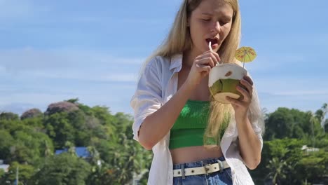 young woman enjoying coconut water outdoors