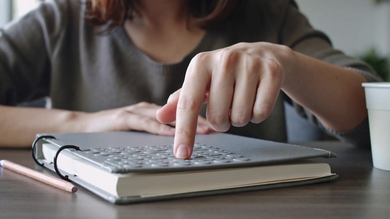 デスクで、スリムなキーボードを使い、右の人差し指で着実にタイピングを始める女性とカップ。
