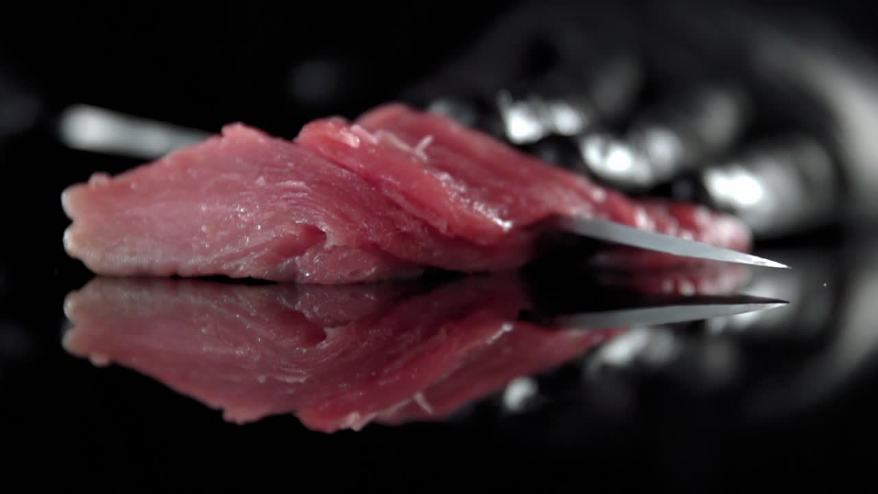 una persona con guantes negros corta un trozo de carne con un cuchillo