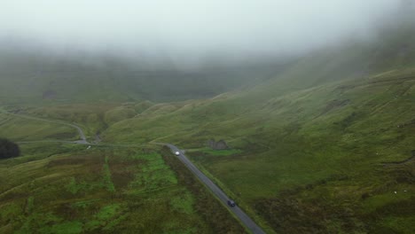 Vista-Aérea-De-Un-Coche-En-Una-Carretera-En-Medio-De-Las-Montañas-En-Irlanda