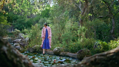mujer glamurosa posando paisaje de madera cerca de claro hermoso lago con lirios de agua