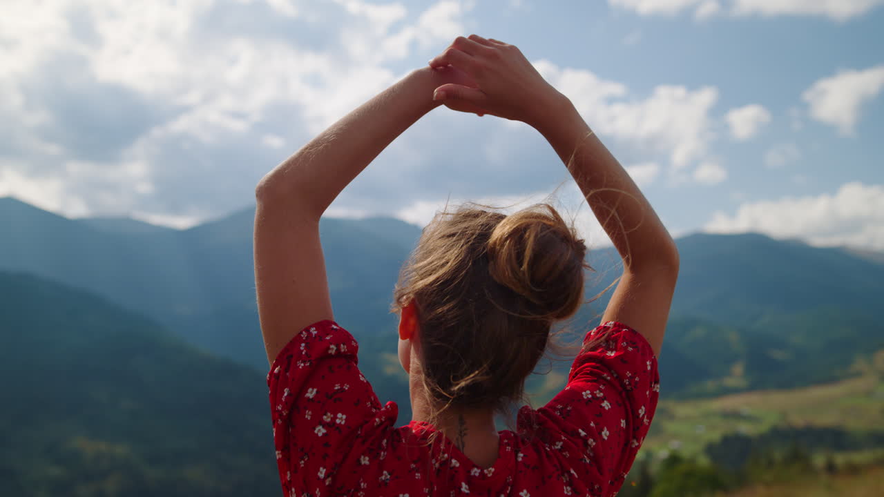 mujer admirando la vista de las montañas de pie en la colina de cerca. niña levantando las manos.