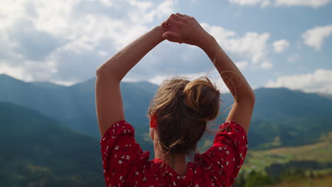 woman admiring mountains view standing on hill close up. girl raising hands.