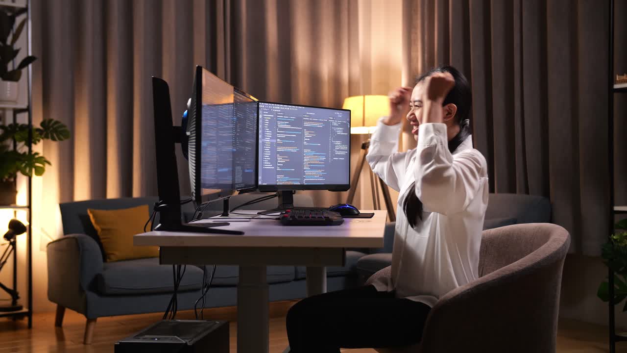 아시아 여성 프로그래머가 성공을 축하합니다. 소프트웨어 엔지니어가 집에서 데스크 컴퓨터에서 앱, 프로그램, 비디오 게임을 개발합니다. 코딩 언어를 가진 터미널.