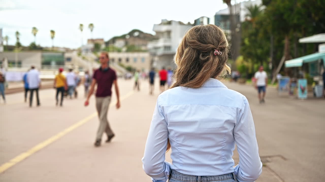 Rear view of a walking woman, walking people on an embankment street in Cannes, France. Slow motion