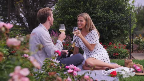 man and woman sip champagne at the same time in rose gardens