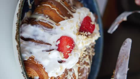 close-up of a decadent croissant topped with whipped cream, strawberries, and chocolate