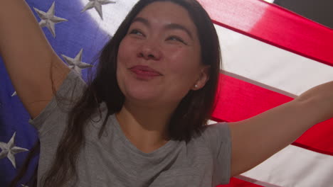 retrato de estudio de cerca de una mujer envuelta en la bandera estadounidense celebrando el 4 de julio, día de la independencia 1