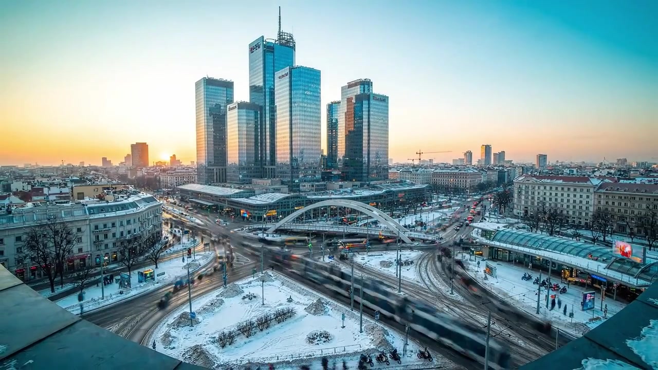 Une soirée d'hiver dans un paysage urbain : Un horizon magnifique de bâtiments modernes au milieu de rues enneigées au coucher du soleil, avec la vie citadine qui s'anime.