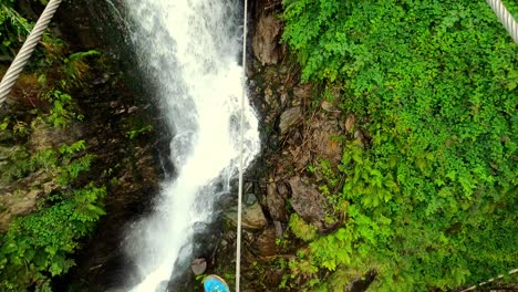 PoV-shot-of-a-man-walking-towards-and-above-a-waterfall-on-a-steel-cable