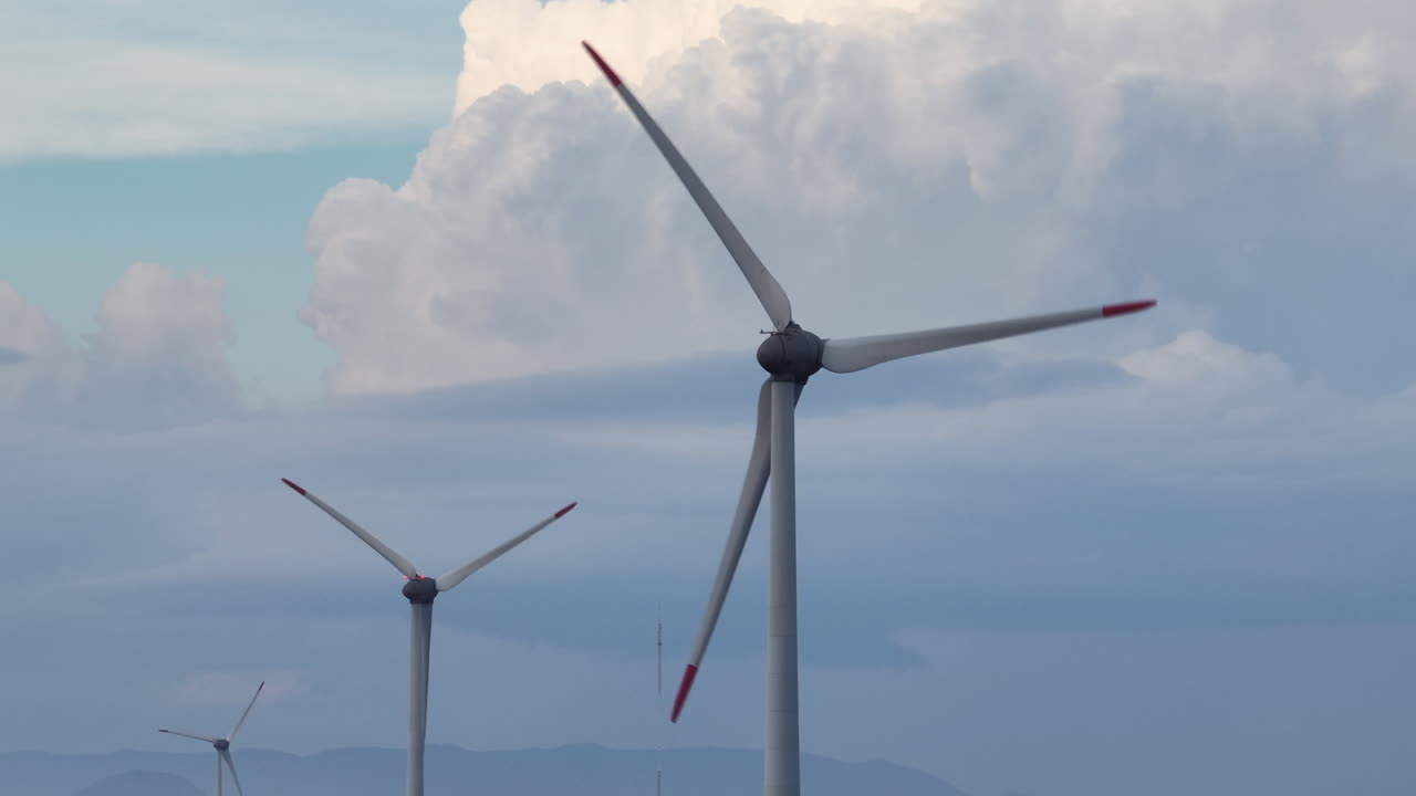Vista teleobiettivo statica con obiettivo lungo di turbine eoliche su tre piani visivi con cielo drammatico di nuvole cumulonembi a Nova Tramandai, Brasile. Filmato video 4K a 60 fps a 10 bit D-Log