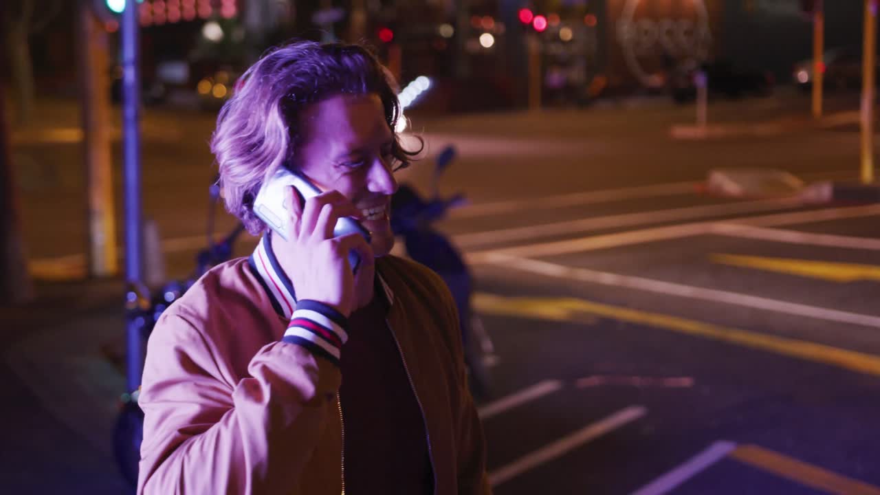 hombre caucásico sonriendo y hablando por teléfono por la noche