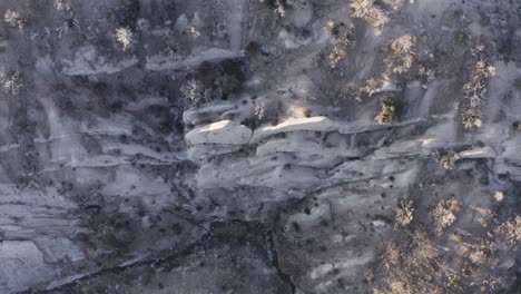 Top-down-view-on-a-rocky-and-dry-sand-area-on-a-sunny-day-with-a-small-river,-slow-motion