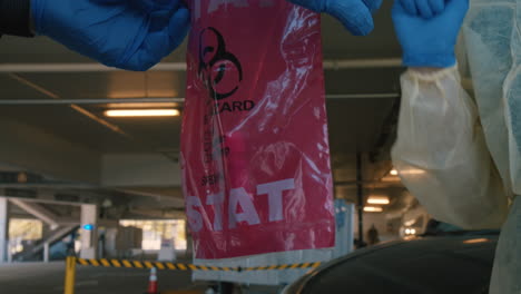 coronavirus or covid-19 test, nasal swab in tube being placed in bio hazard bag by nurse