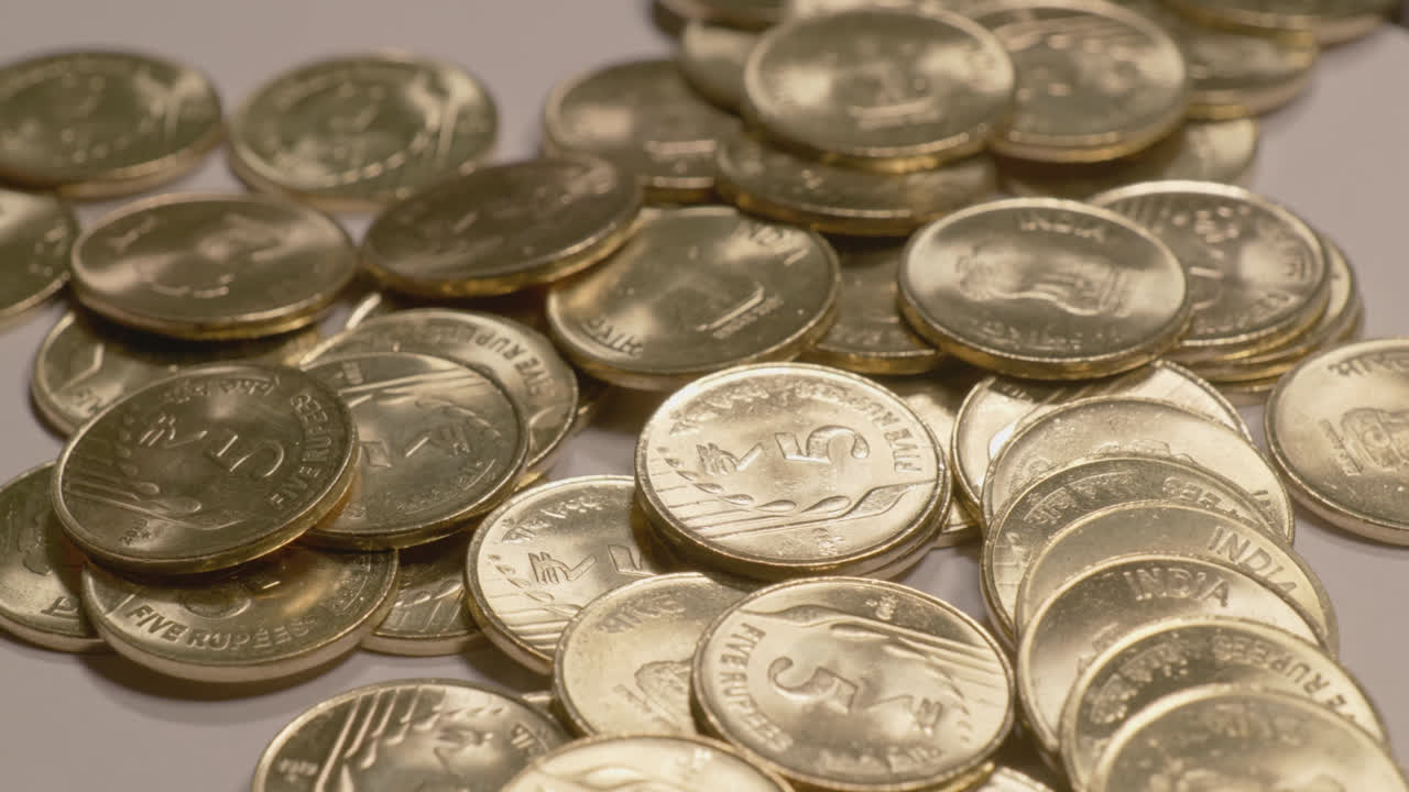 indian currency golden 5 rupee coins scattered on the table , 4k close up, orbit shot
