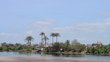 Egyptian-Buildings-Surrounded-by-Palm-Trees-by-the-Nile-River