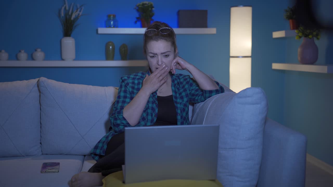 mujer viendo una película en el portátil por la noche en casa.