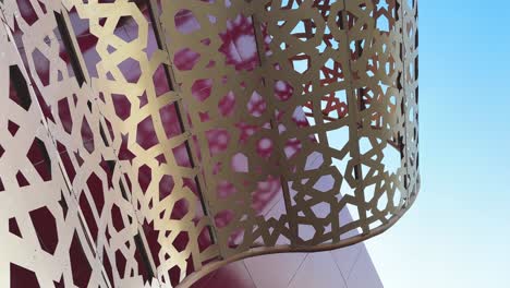 modern building is a luxury shopping mall has contemporary art design brand new architectural creative idea design like a gift box shape with red color golden ribbon islamic pattern and the sky in day