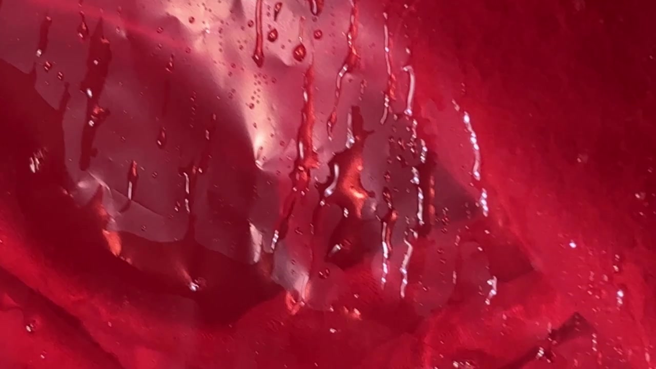 Water Droplets Sliding Down Red Fabric Surface