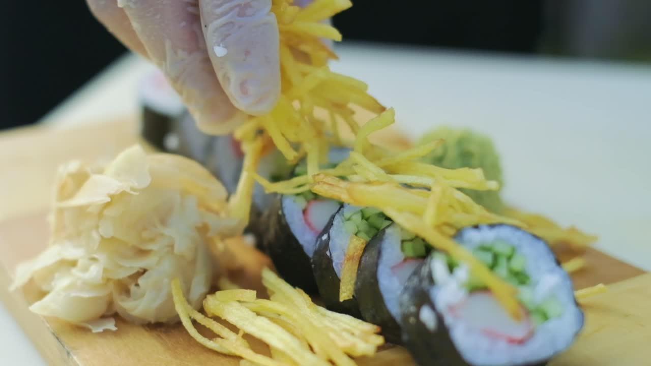 primer plano de sushi japonés fresco en un plato con el chef del restaurante decorando rollos con papas fritas sirviendo preparando