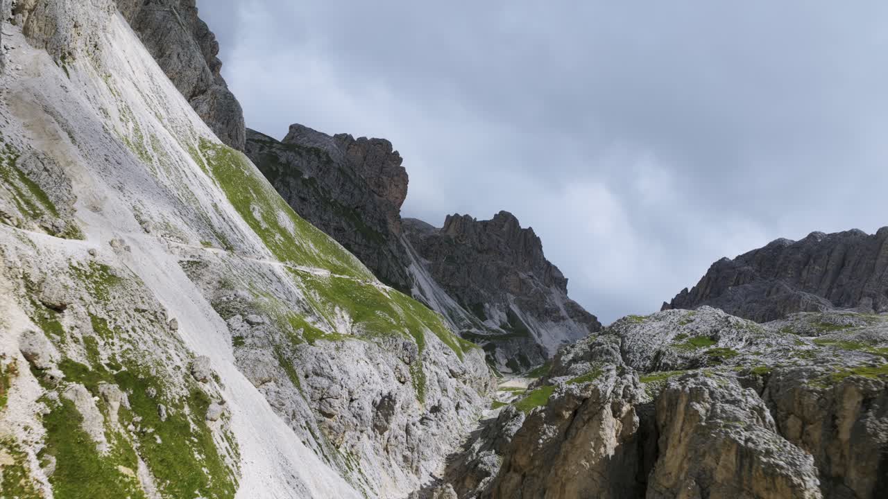 Aerial view of dramatic mountain ridge. Shows steep scree slopes and jagged peaks under moody cloudy sky. For nature or hiking content, Vajolet, Dolomites, Italy