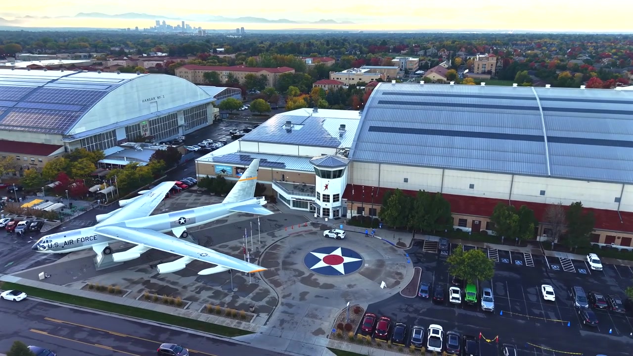 Órbita corta de dron alrededor de la entrada del Museo del Aire y el Espacio Wings Over the Rockies en Denver, Colorado, con los terrenos circundantes visibles bajo la luz del atardecer