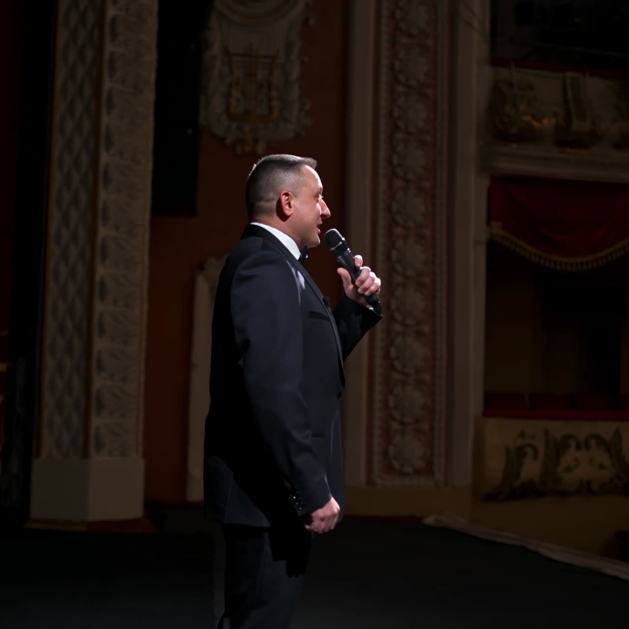 Actor steps on classic theater stage. Man in suit is walking in spotlights during the performance. Classic theater concept
