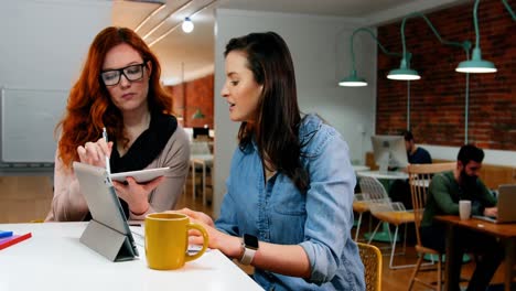 female executives discussing over digital tablet