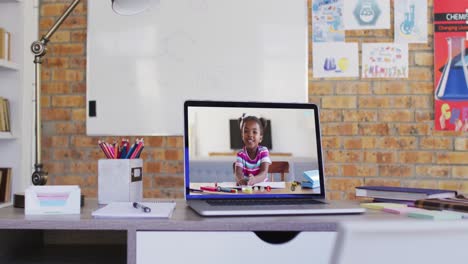 Webcam-view-of-african-american-school-girl-on-video-call-on-laptop-on-table-at-school