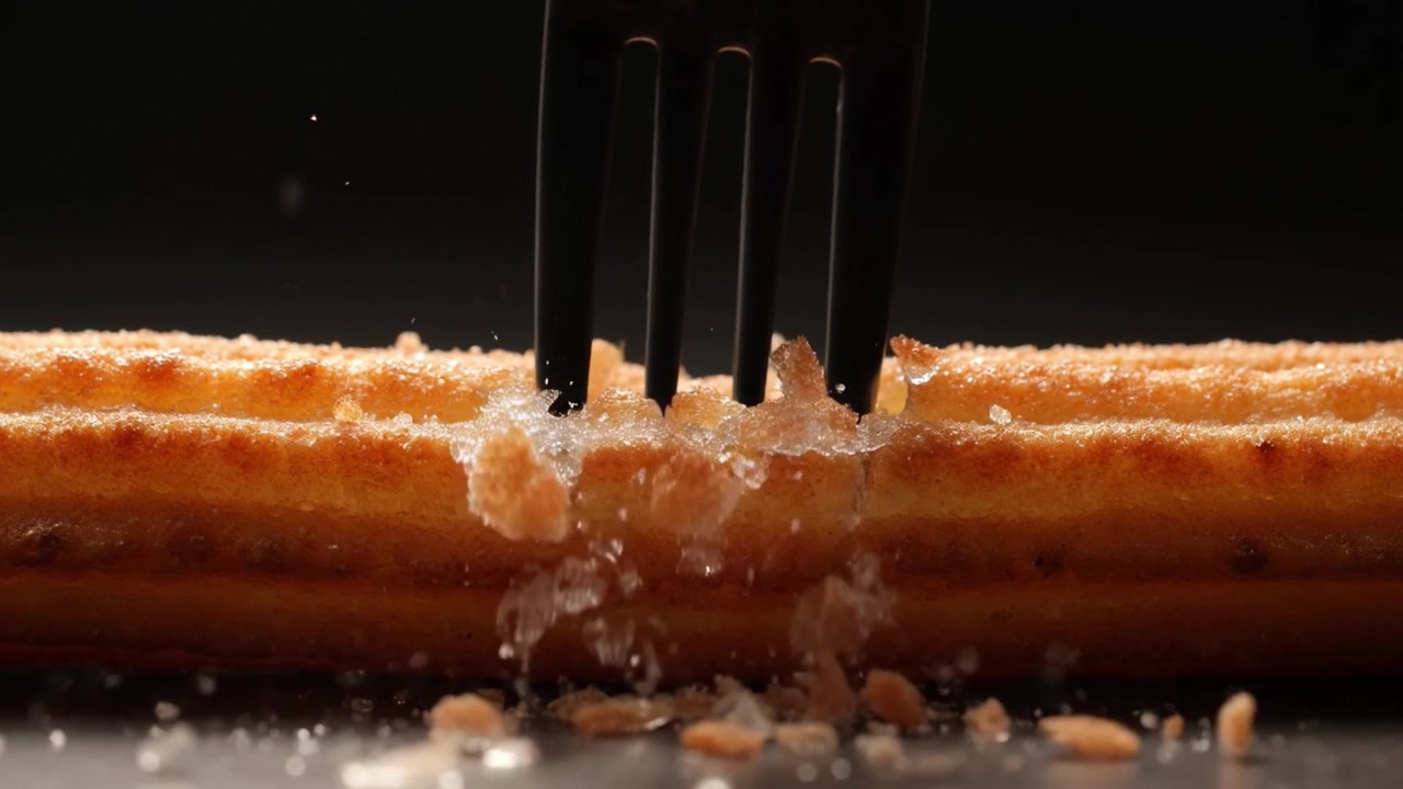 Forchetta che spezza un churro croccante in primo piano