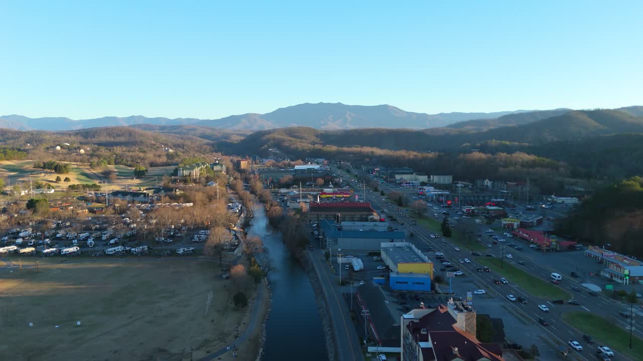 Drone shot pulling out and panning to reveal the Smoky Mountains outside of Downtown Piegon Forge, TN.