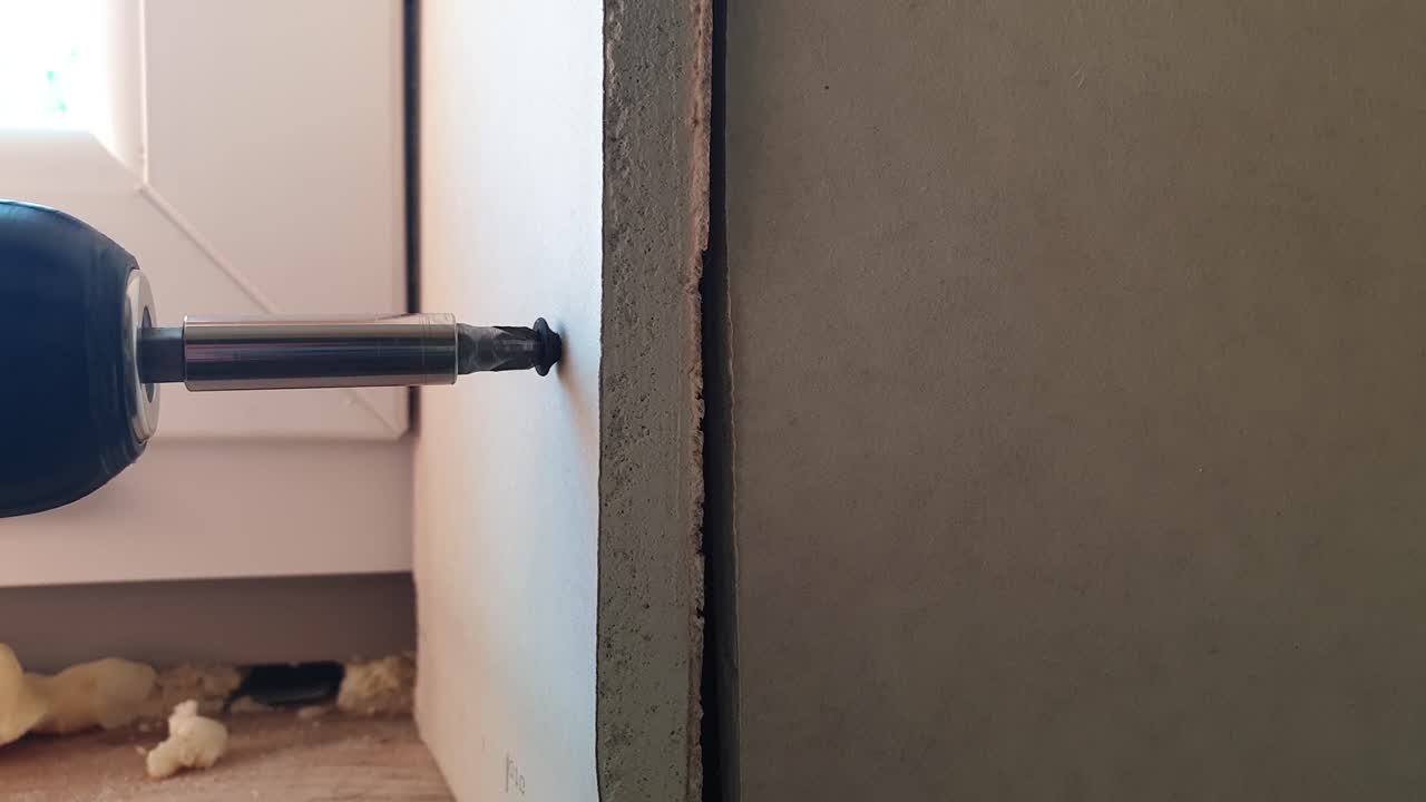 toma manual de atornillar un panel de yeso a una pared de la casa que está en construcción