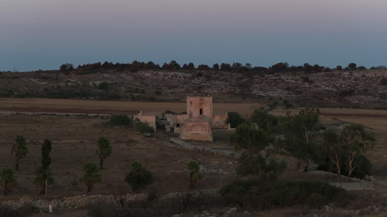 Historic Masseria Cippano ruins at dusk, fortified farmhouse in rural landscape, Puglia, Italy. Aerial drone orbiting