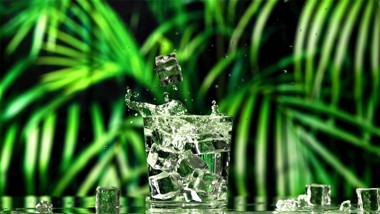 Movimento rallentato di cubetti di ghiaccio che si tuffano in un bicchiere d'acqua