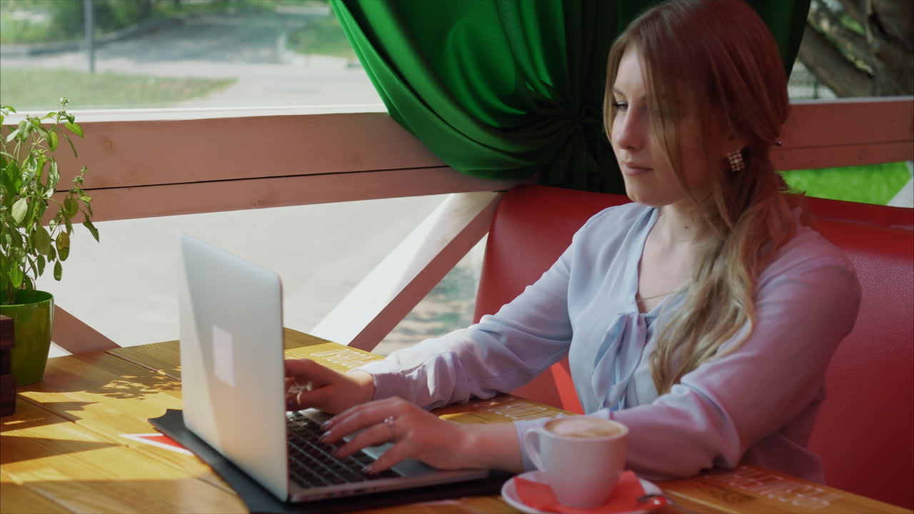 Kvinde, der arbejder på bærbar computer på en café