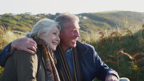 loving active senior couple hugging as they sit and look at countryside together