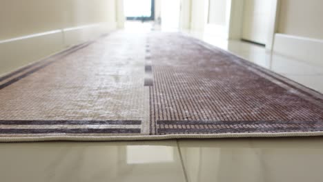 a long beige and brown striped rug laid out on a tiled hallway floor