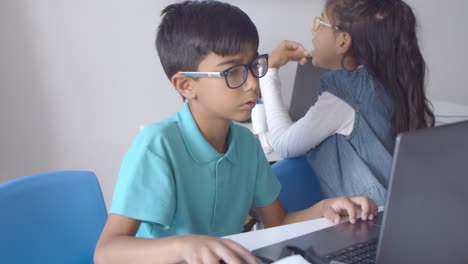 serious school boy in glasses sitting at desks