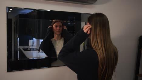 female model looking at herself, reflection and sorting out her hair in a mirror