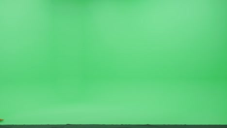 pantalla verde chroma clave estudio: hermosa mujer joven con ropa casual elegante camina a través de la habitación de izquierda a derecha. vista lateral disparada por la cámara