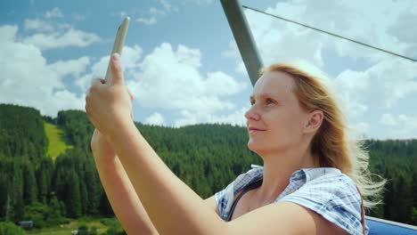 Eine-Aktive-Frau-In-Der-Kabine-Eines-Skilifts-Fotografiert-Schöne-Aussichten-Auf-Berge-Und-Wälder-Holi